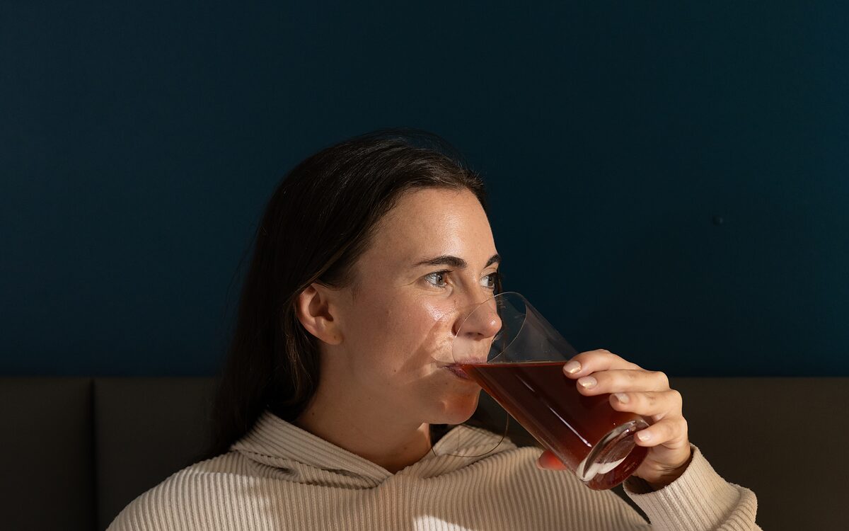 A woman drinking a prepared Winks drink in a dim room at night