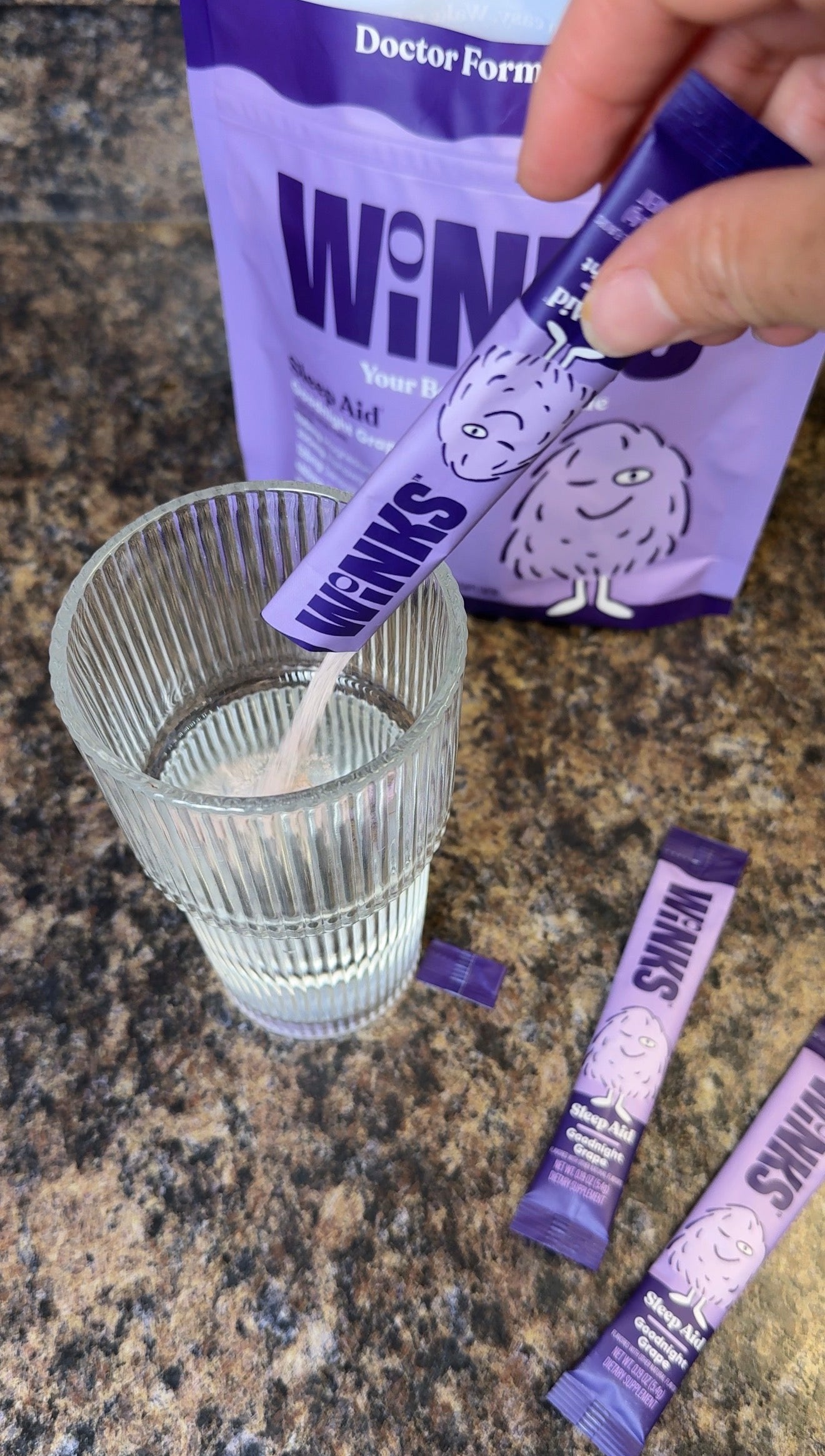 Heather pouring a Winks stick into a glass of water on her kitchen counter