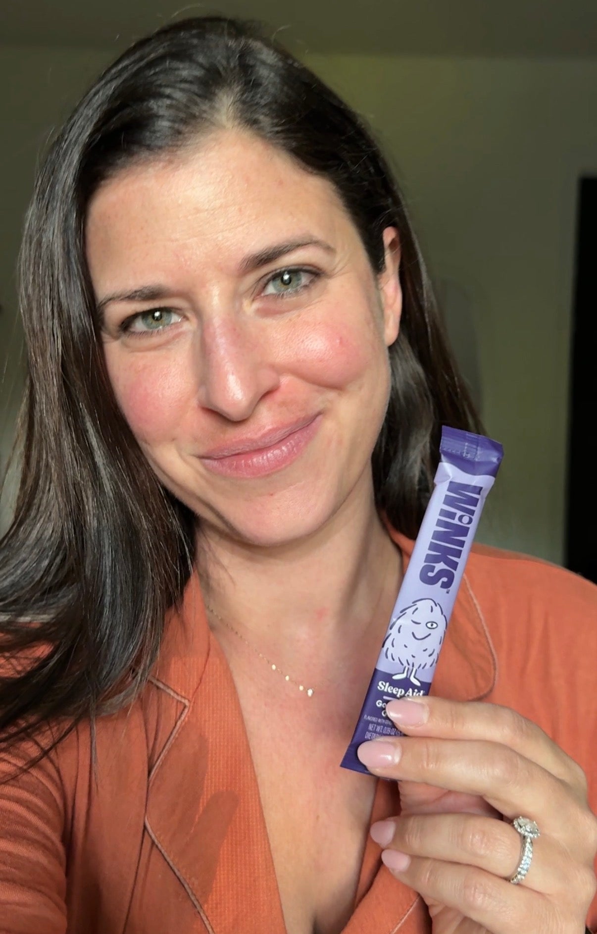 Caitlin holding a Winks stick pack while wearing pajamas