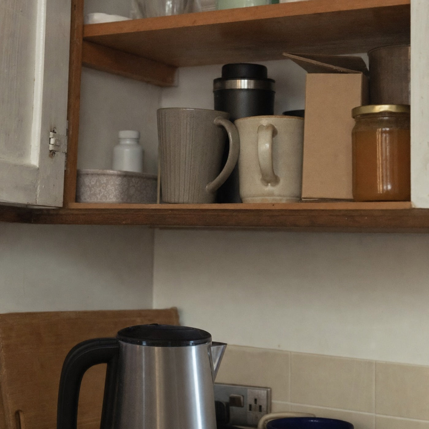 An open kitchen cupboard, a plain unlabelled bottle pushed to the back