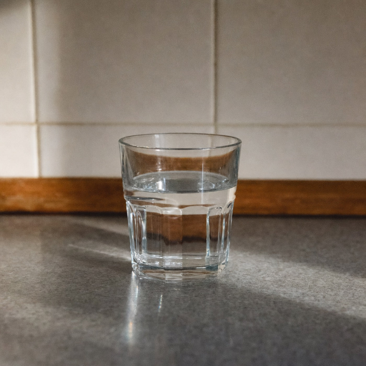 A single plain glass of tap water alone on a bare worktop