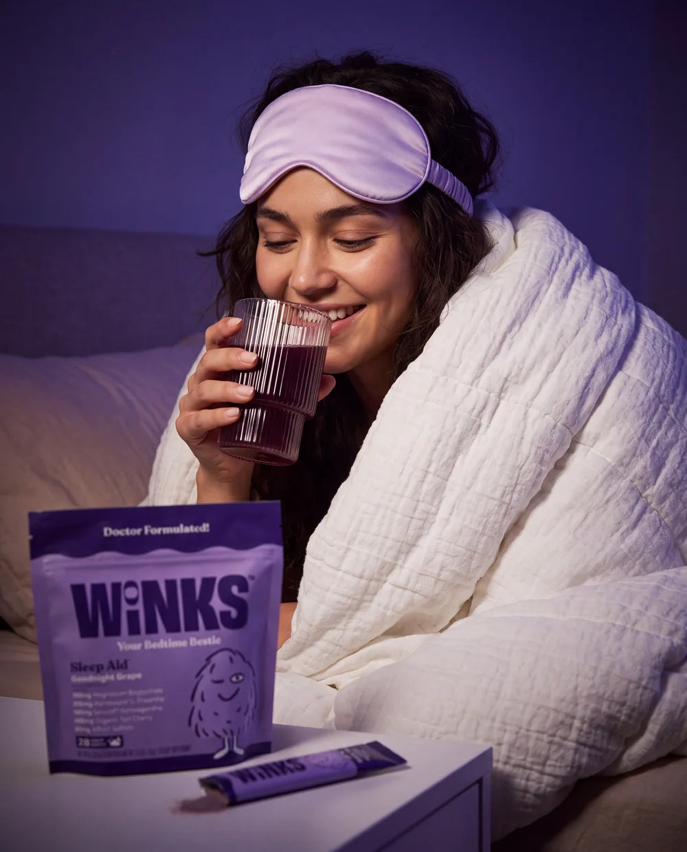 A woman holding her bedtime drink with Winks beside her