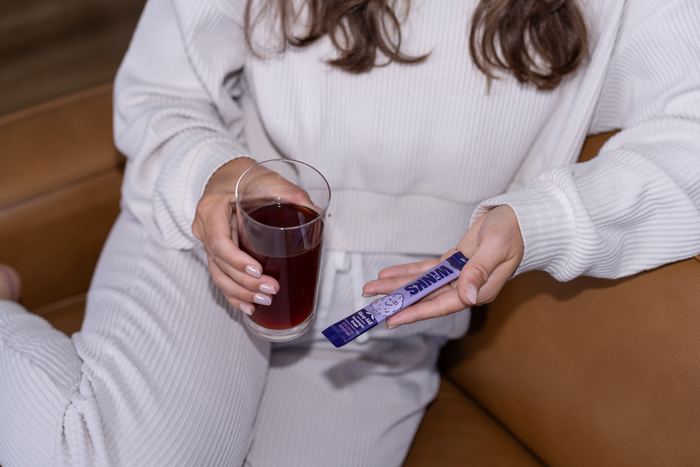 Winks studio photograph of a woman holding her evening drink and a Winks stick