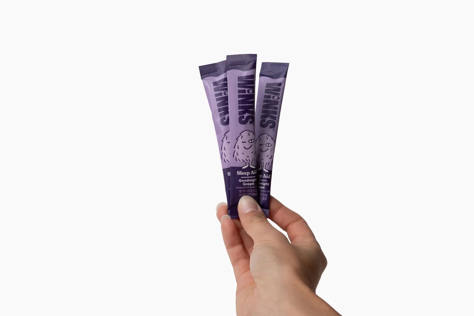 A hand holding Winks Goodnight Grape stick packs