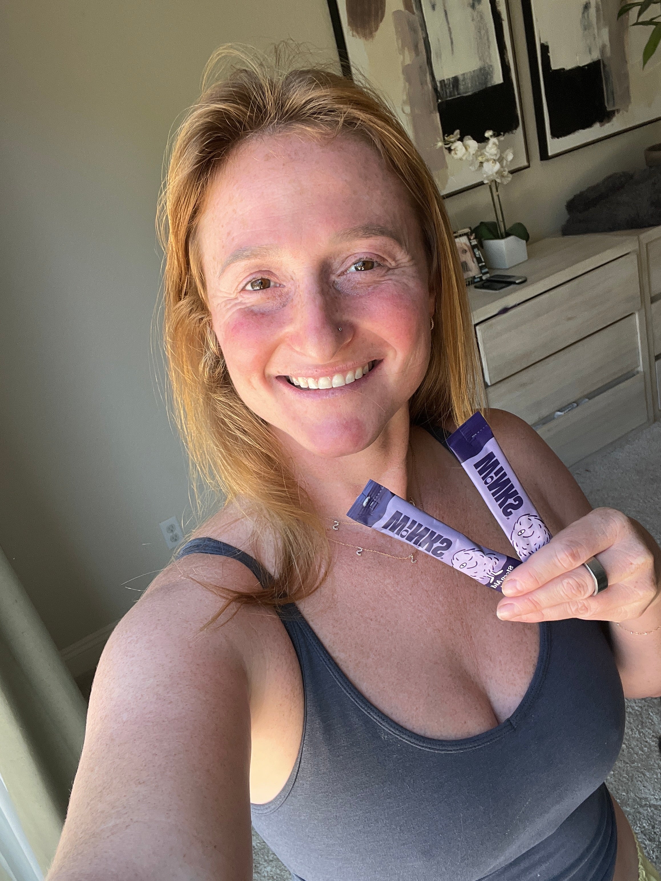 Ashley holding two Winks stick packs in a bedroom